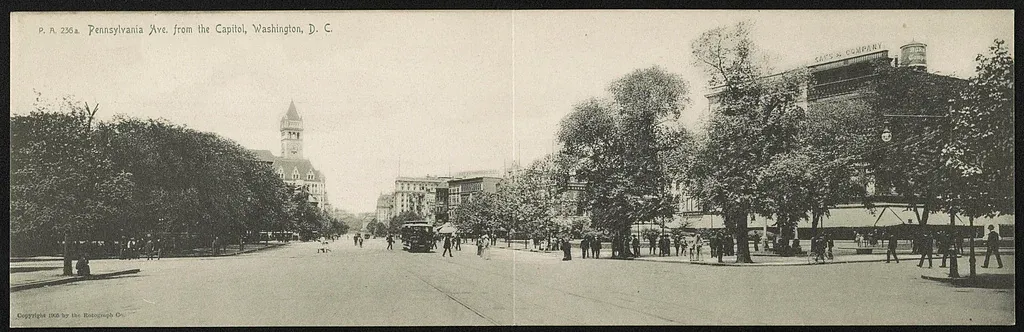 Panoramic historic postcard looking west along Pennsylvania Avenue in Washington, with a streetcar, pedestrians, trees and commercial buildings.