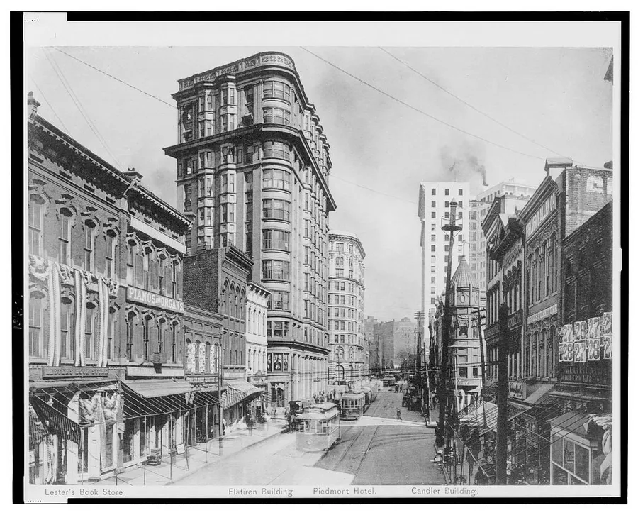 Historic black and white print of Atlanta's Lower Peachtree Street, with streetcars, shops and tall buildings along the road.