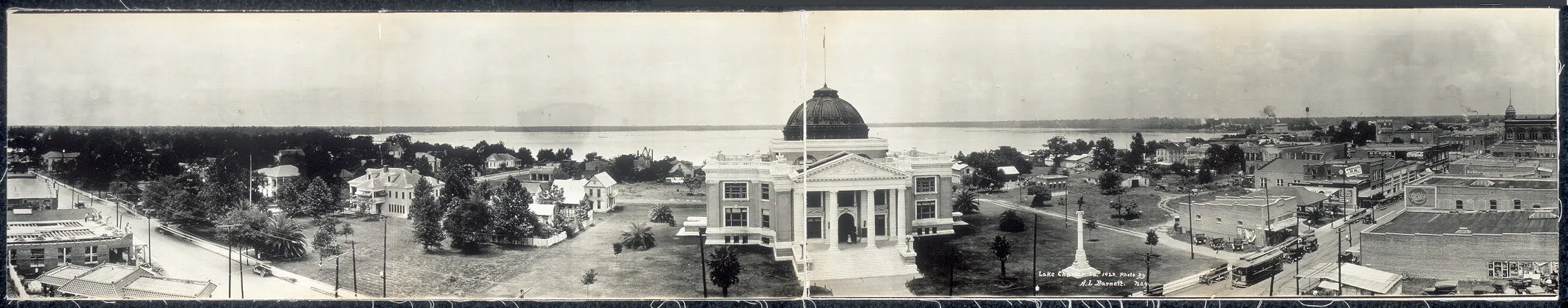 A wide black-and-white panorama of central Lake Charles with a domed civic building and the waterfront beyond.