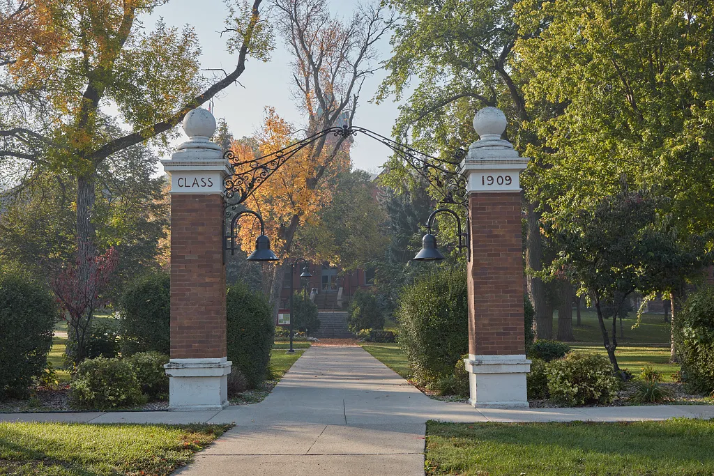 Stone entrance pillars and an autumn walkway at Valley City State University